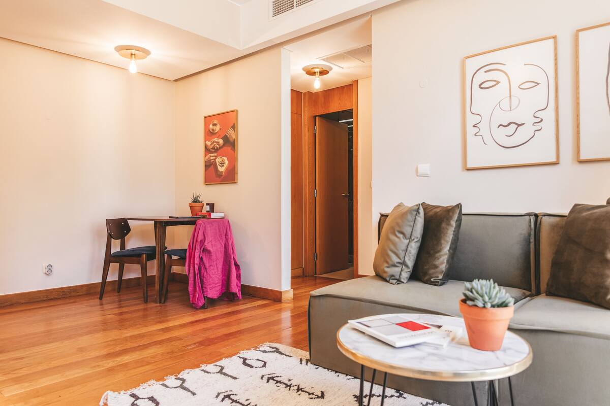Un salon comprenant un canapé, une table basse, une table à manger avec des chaises, et des œuvres d’art accrochées aux murs.