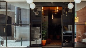 L’entrée d’un hôtel, avec un auvent incurvé, des portes en verre et un pot de fleurs.