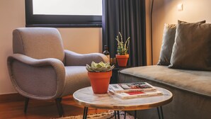 Un salon avec un fauteuil à motifs à carreaux, une table basse ronde sur laquelle est posée une plante succulente en pot, et un canapé agrémenté de coussins.