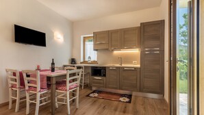 Una cocina moderna con armarios de madera, una mesa de comedor con sillas, un televisor de pantalla plana y una ventana con vistas.
