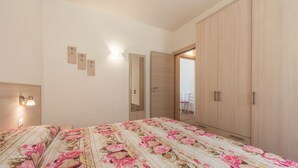 Un dormitorio con cama, armario, espejo e iluminación en la pared.