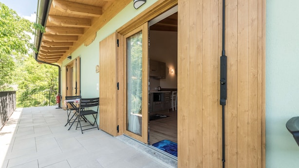 A wooden exterior with a sliding glass door leading to a kitchen area.