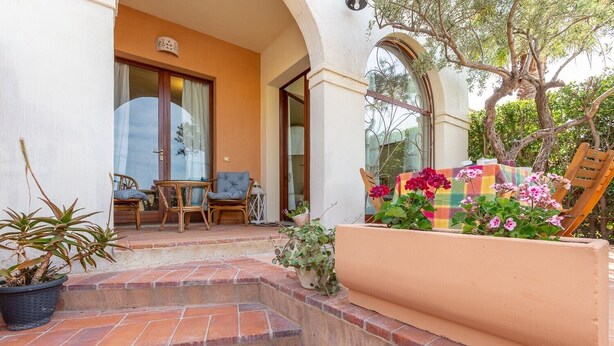 Un patio con escalones que llevan a una zona de estar, una jardinera con flores y vistas al follaje circundante.
