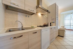 A modern kitchen with a built-in dishwasher, stainless steel sink, and a gas stove. - Holiday Apartment "Elga" with Garden & Wi-Fi (Villasimius)