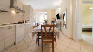 Una cocina moderna con comedor, horno empotrado y mesa con sillas.