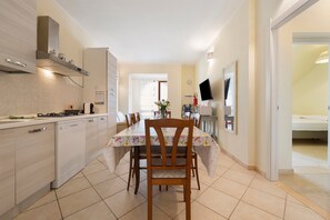 A modern kitchen with a dining area, a built-in oven, and a dining table with chairs. - Holiday Apartment "Elga" with Garden & Wi-Fi (Villasimius)