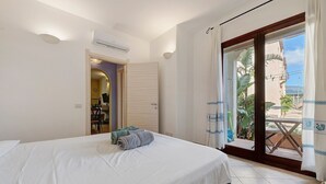 Una habitación de hotel con una cama, una puerta que da a un balcón y un equipo de aire acondicionado.