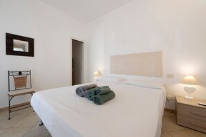 Habitación de hotel con cama, una silla, una mesita de noche, una lámpara y un espejo en la pared.