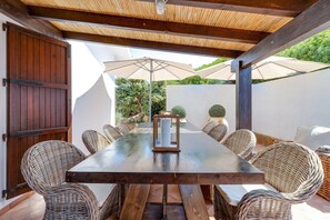 A covered outdoor dining area with a wooden table and wicker chairs, surrounded by umbrellas. - Vacation Home "Casa de S Arca 3" with Spectacular Sea View, A/C, Garden, Terrace & Barbecue (Pistis - Arbus)