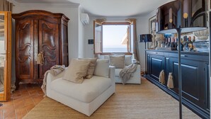 Ein Wohnzimmer mit einer Couch, einem Holzschrank und Blick ins Freie.