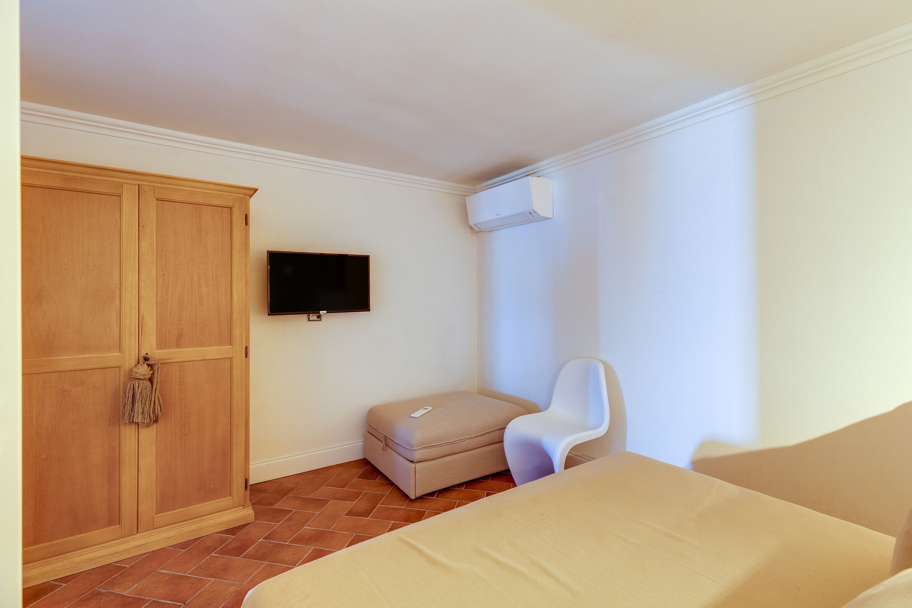 Una camera da letto con un letto, un armadio, una televisione e un piccolo angolo relax.