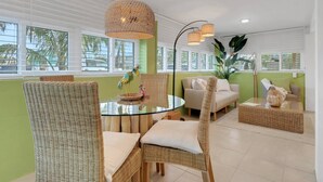 Een moderne woonkamer met rieten meubels, een glazen salontafel en een hanglamp.