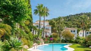 A pool surrounded by lush greenery and white buildings with balconies.