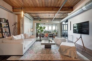 A modern living room with a white sofa, a coffee table, and a TV on the wall.