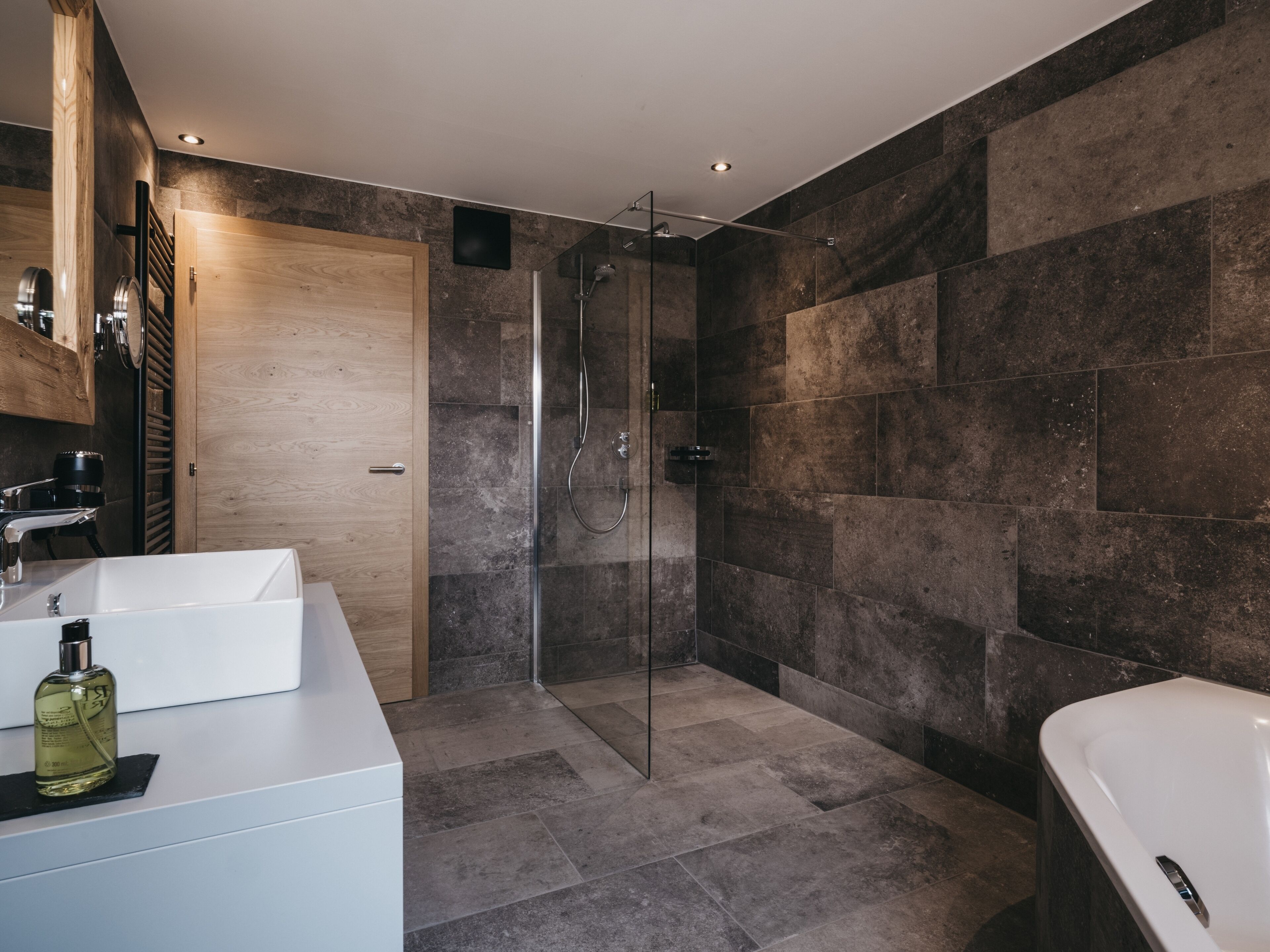 Une salle de bain moderne avec une douche à parois de verre, un lavabo blanc et une baignoire.