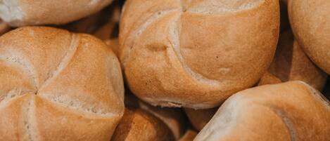 A close-up of a large number of round, golden-brown bread rolls with a braided pattern.
