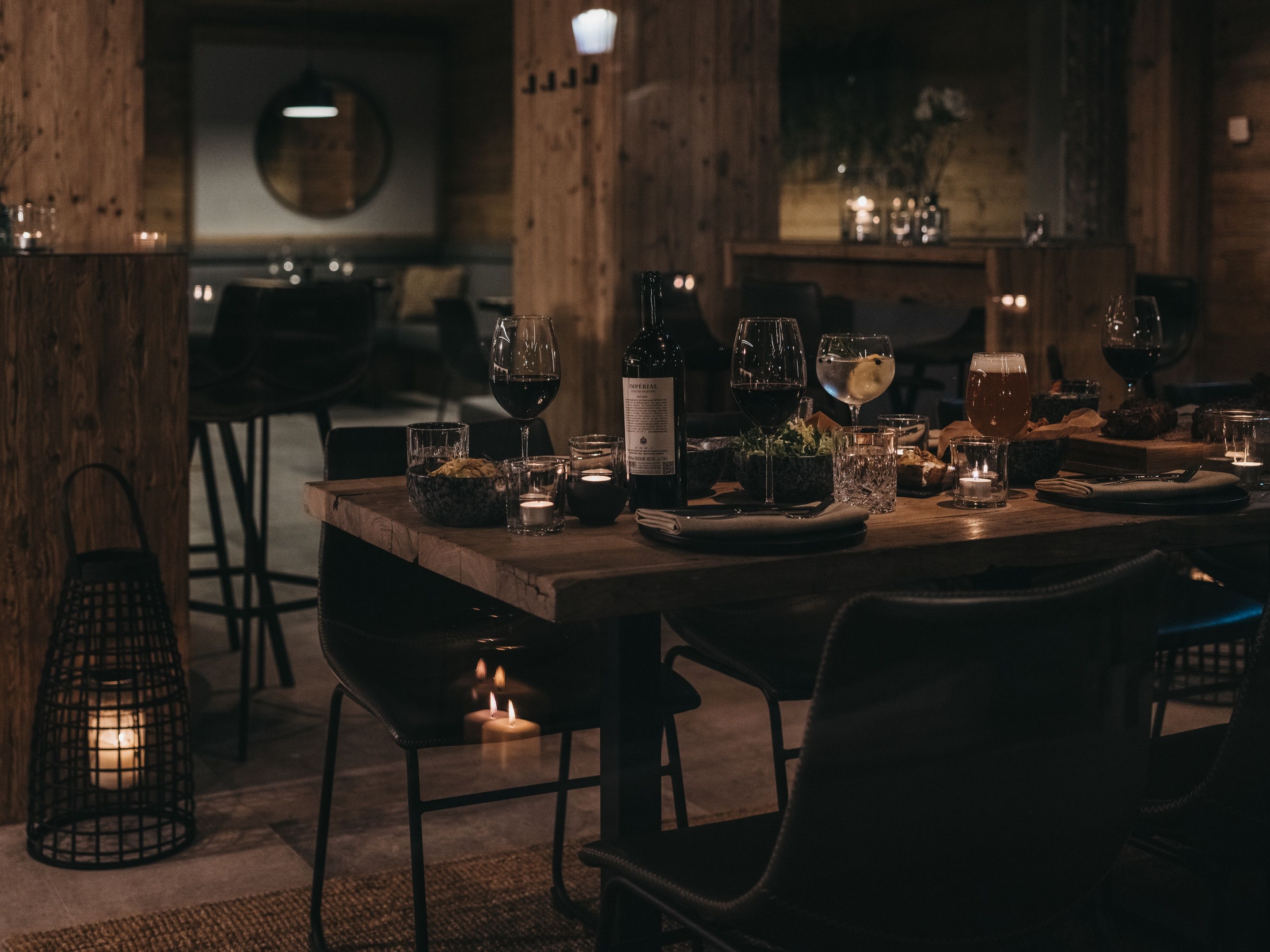 A dimly lit restaurant with wooden furniture, candles, and a menu on the table.