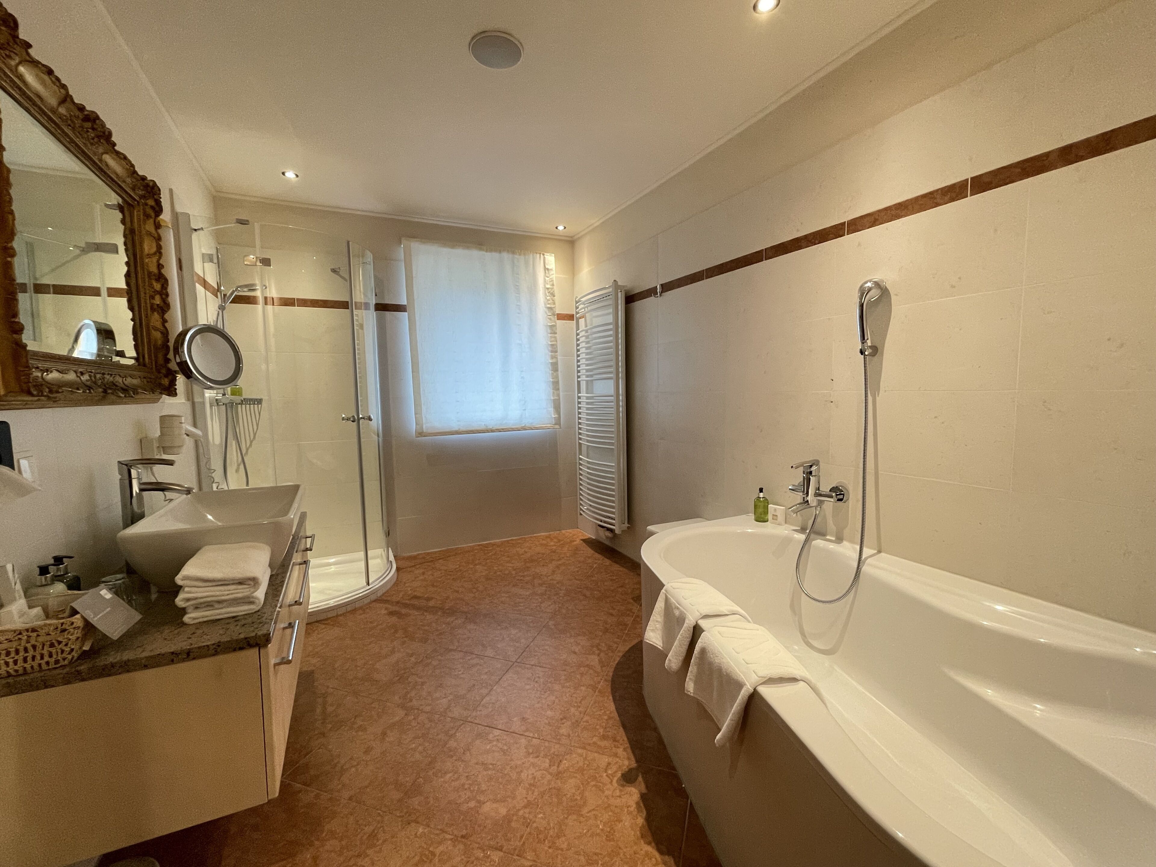 A modern bathroom with a bathtub, shower, and vanity.