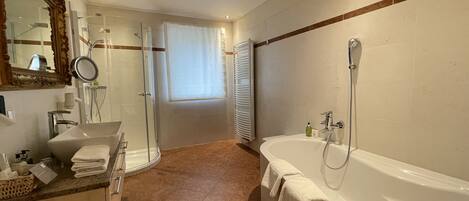 A modern bathroom with a bathtub, shower, and vanity.