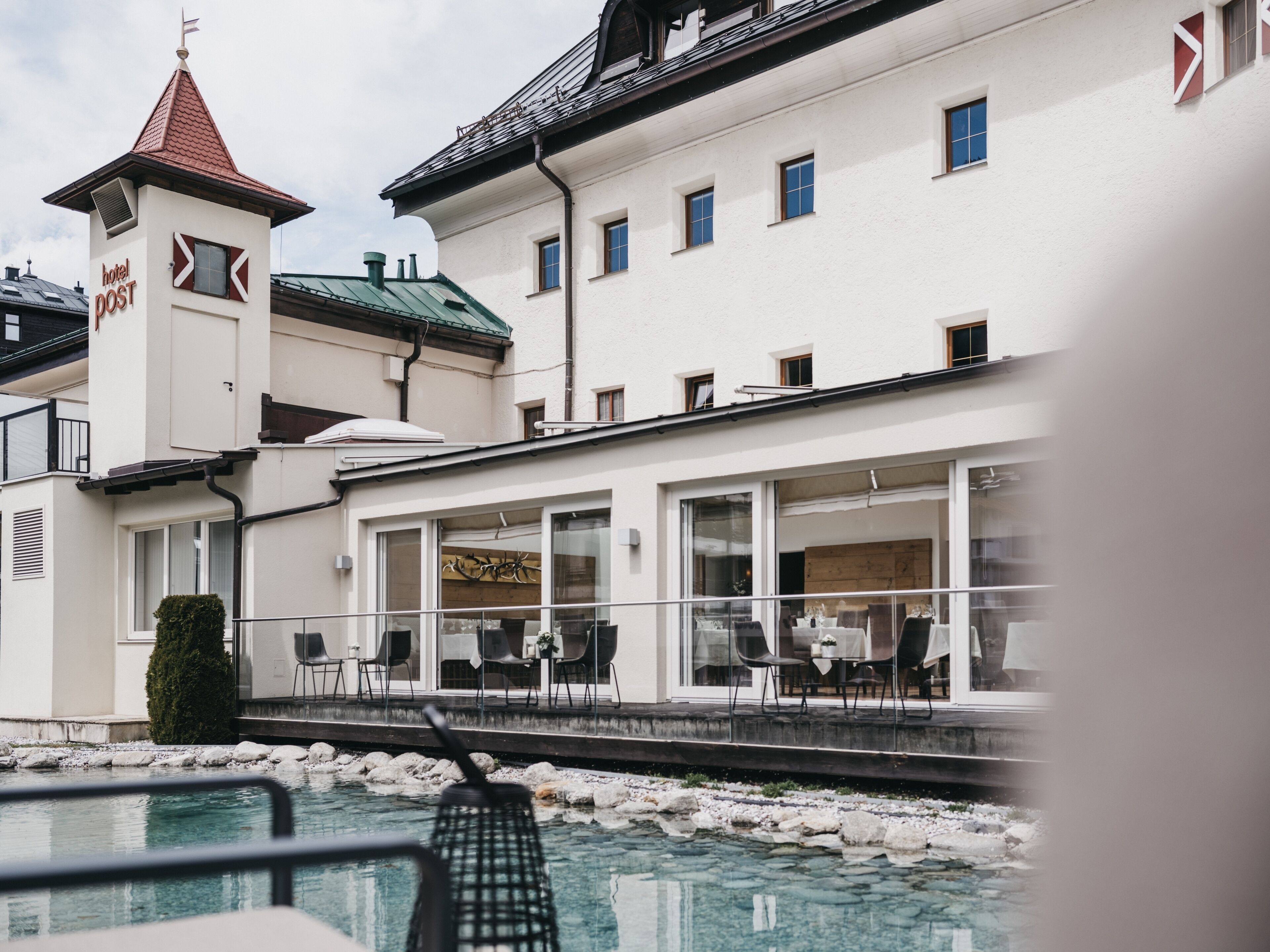 Un hotel con area piscina, posti a sedere all'aperto e una torre con una bandiera.