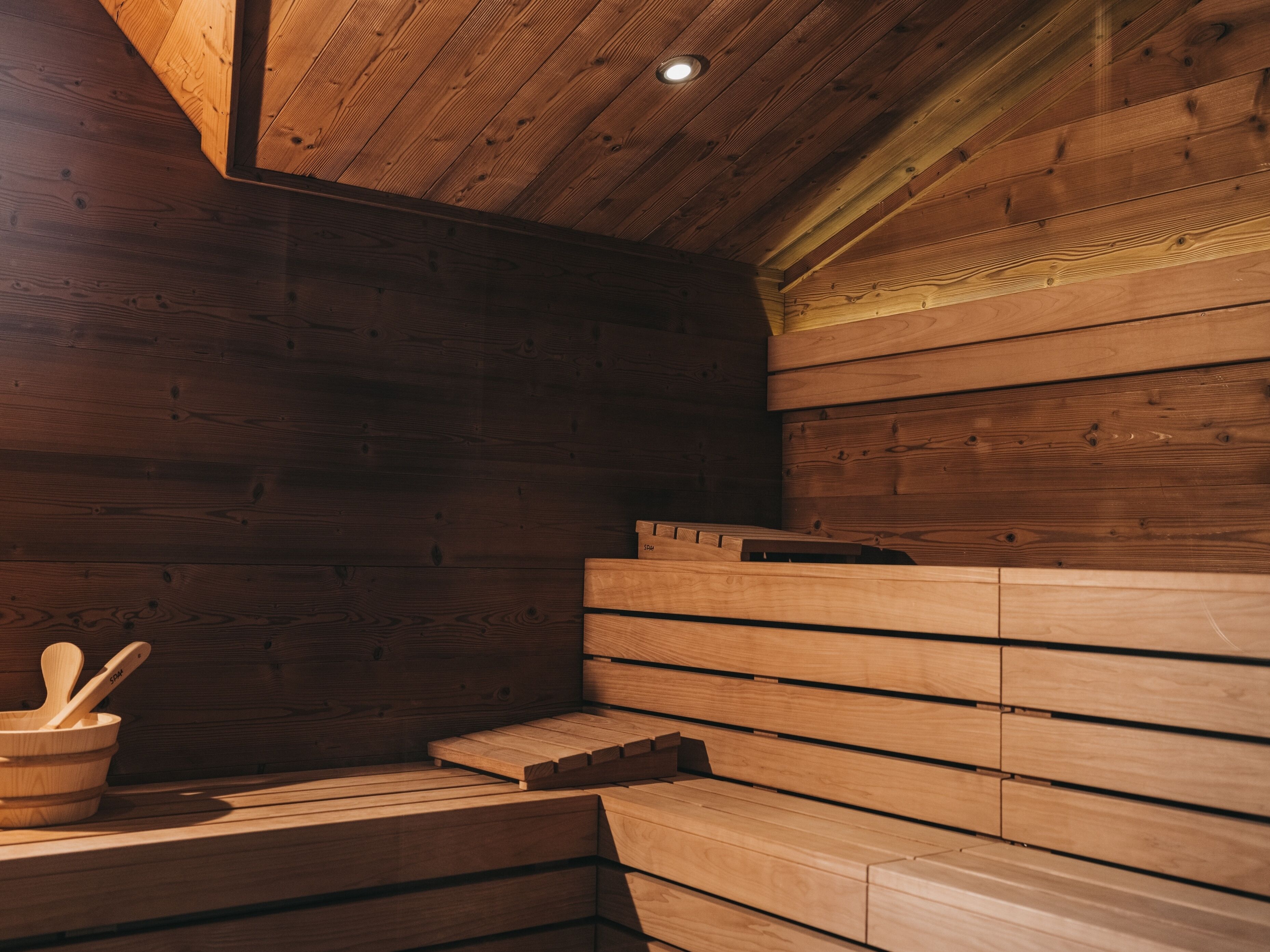 Una sauna con bancos de madera y un cuenco de madera con una cuchara.