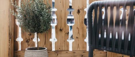 A wooden fence with a potted plant and a chair.
