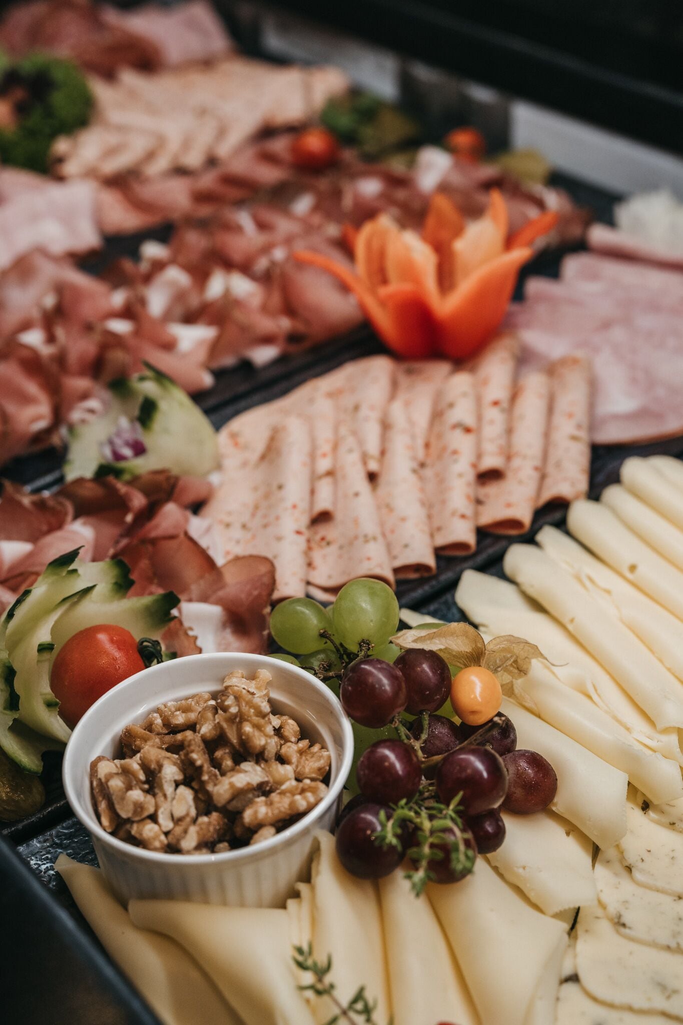 Una tabla de fiambres con diferentes carnes, quesos y frutas.