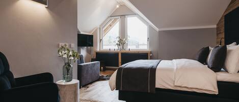 Une chambre moderne dotée d’un grand lit, d’une télévision, d’une cheminée et offrant une vue sur l’extérieur.