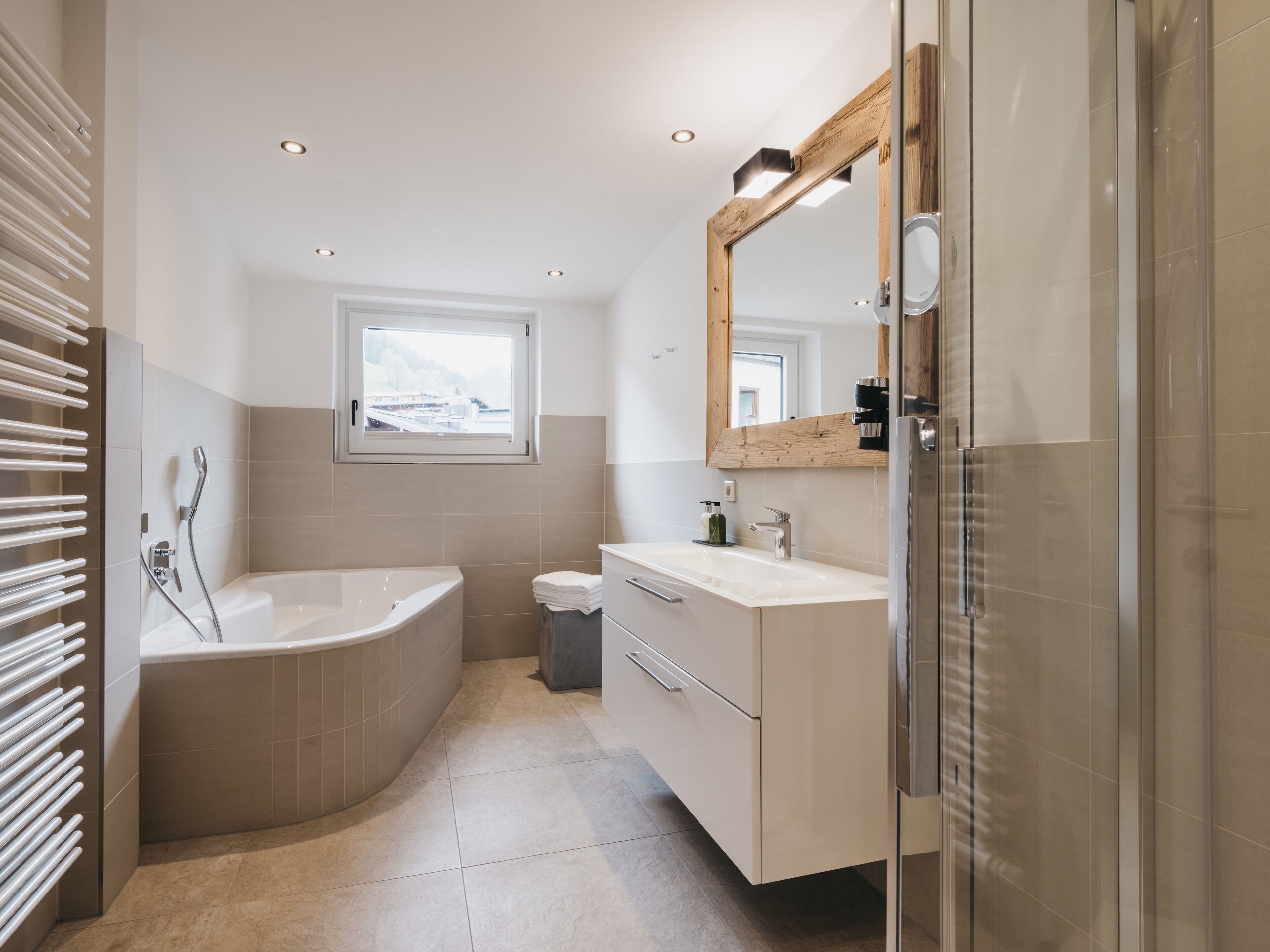 A modern bathroom with a freestanding bathtub, a vanity with a mirror, and a window providing natural light.