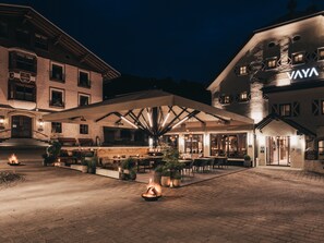A hotel courtyard with outdoor seating, a reception area, and a building with a sign reading 'VAYA'. - VAYA Post Saalbach (Saalbach-Hinterglemm)