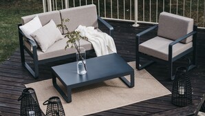 Um terraço com sofá, cadeiras, mesa de centro e lanternas.