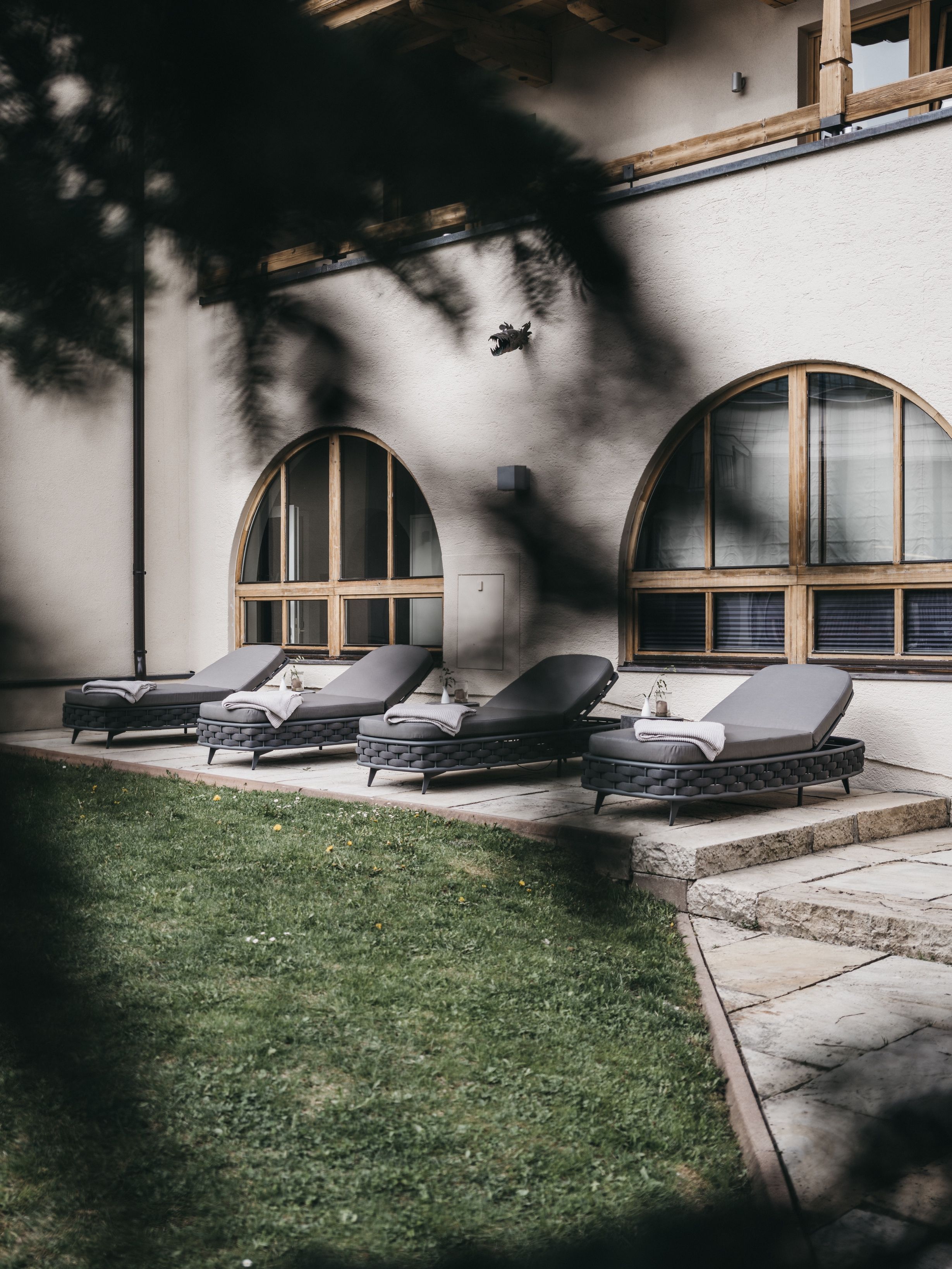 A building with three lounge chairs aligned in front of a large arched window.