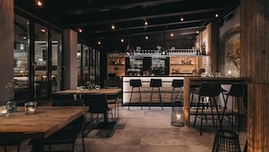 Uma área de bar moderna, com balcão, banquetas e uma grande janela com vista para a rua.