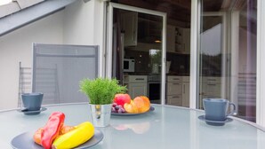 Un comedor con una mesa dispuesta para el desayuno, que incluye cruasanes, frutas y una planta en maceta.