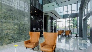 Eine moderne Lobby mit Marmorböden, Ledersesseln und einer Glaswand mit Blick auf Grünflächen.