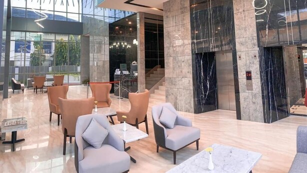Eine großzügige Lobby mit modernen Sitzgelegenheiten, einer Glaswand und einem Marmor-Empfangstresen.