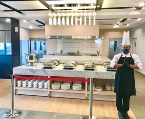 A modern kitchen with a marble countertop, stainless steel appliances, and a service station with cups and plates. - Vasaka Hotel Makassar Managed by Dafam (Makassar)