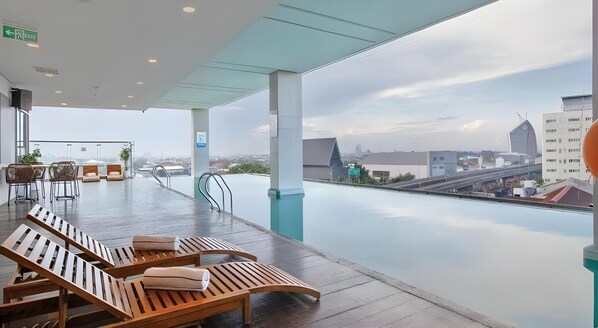 A rooftop terrace with lounge chairs, a dining area, and a view of the cityscape. - Vasaka Hotel Makassar Managed by Dafam (Makassar)