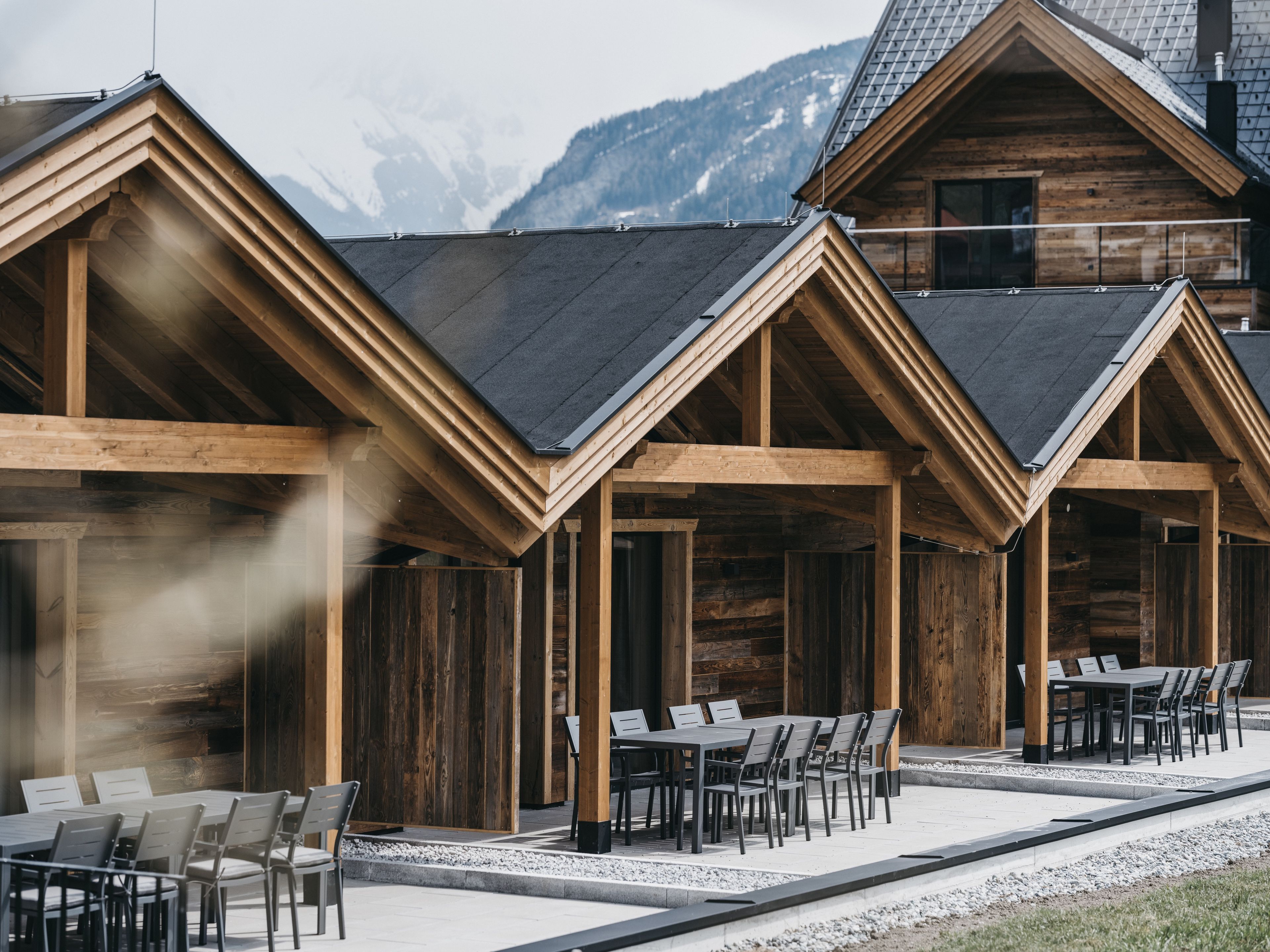 Filetta di cabine di legno con un'area ristoro di fronte, sullo sfondo montagne.