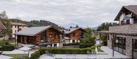 A resort with wooden cabins, a swimming pool, and a mountainous backdrop.