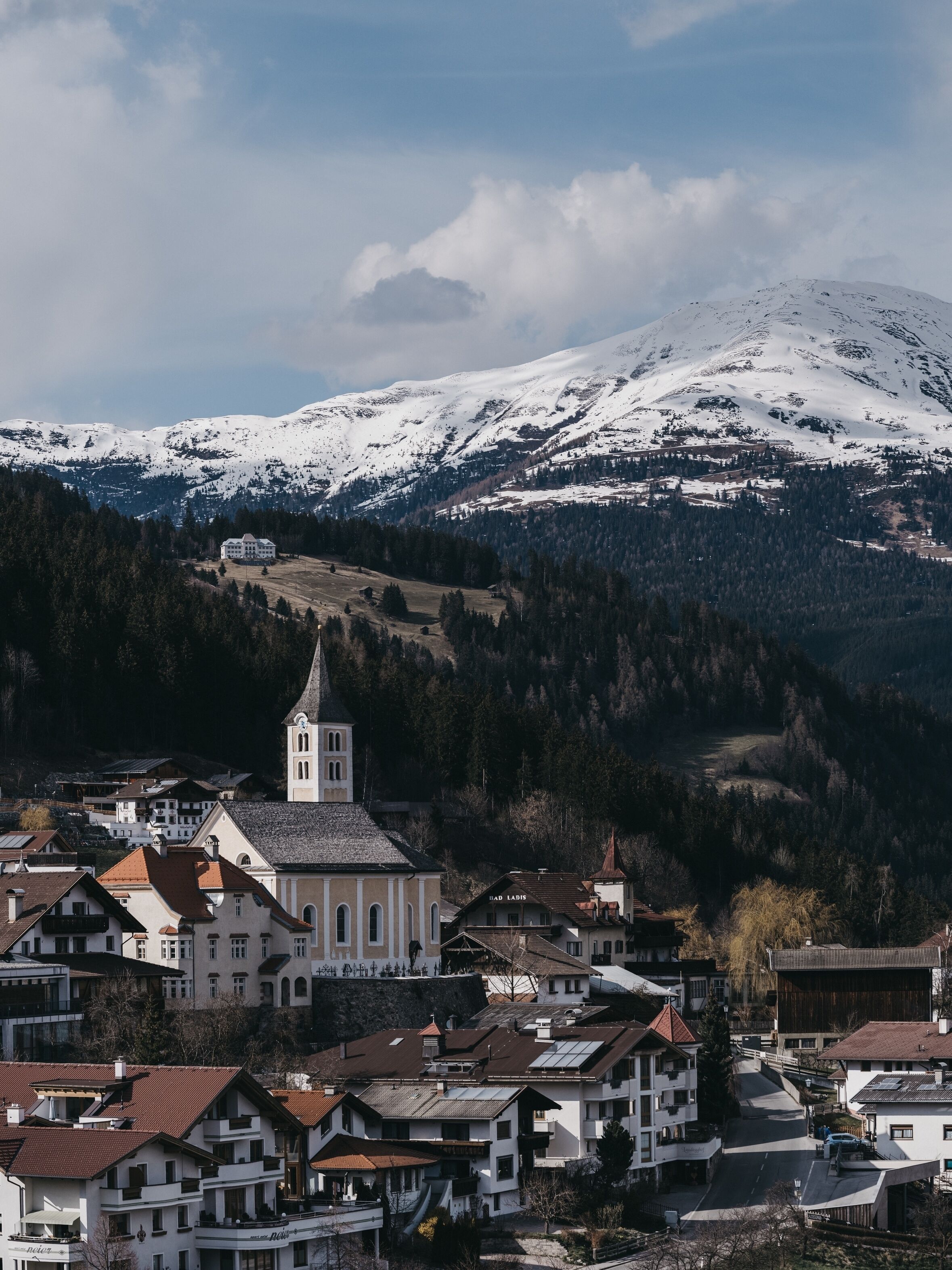 A town with a prominent church and a snow-capped mountain in the background.