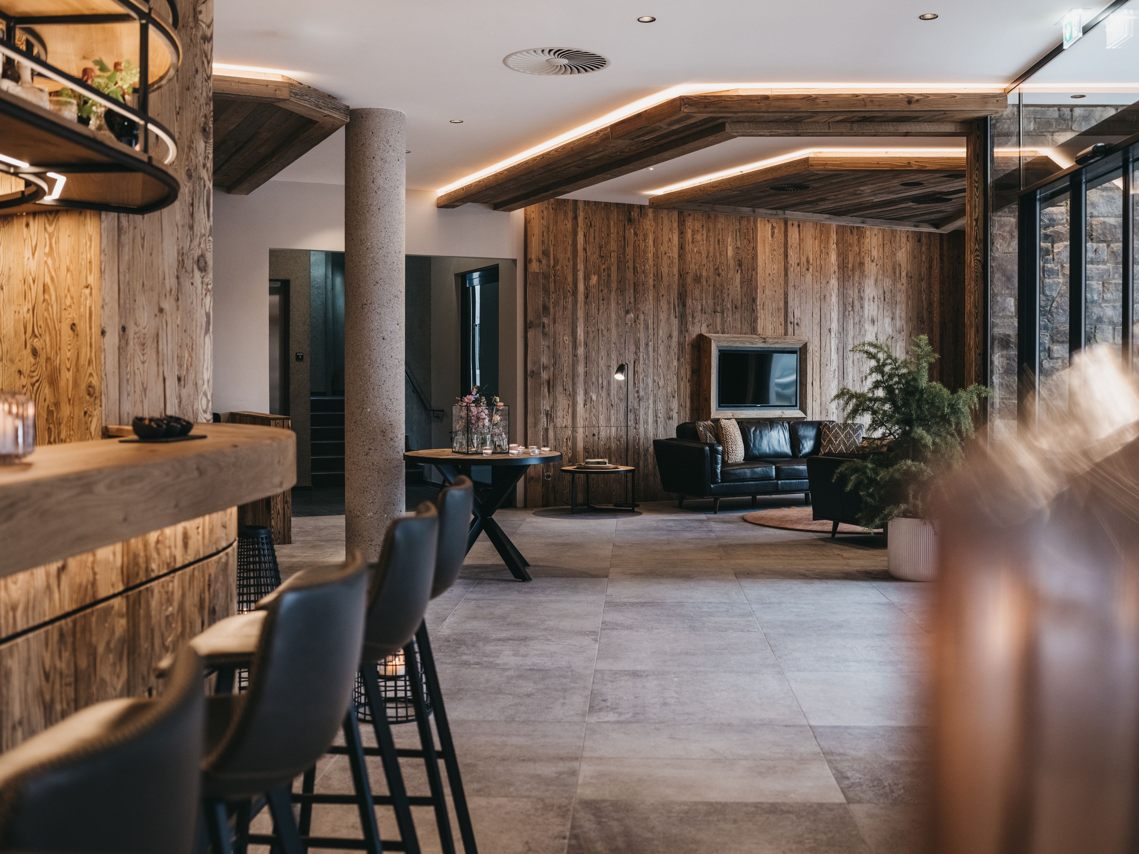 Un intérieur moderne avec des lambris en bois, un coin bar, des sièges et un téléviseur.