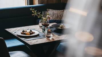Une table à manger dressée avec des assiettes, des verres et un vase de fleurs.