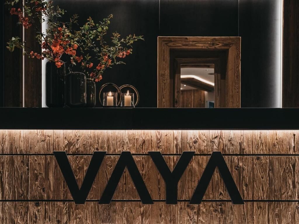 Zona de recepción con mostrador de madera y un gran letrero que dice 'VAYA'.
