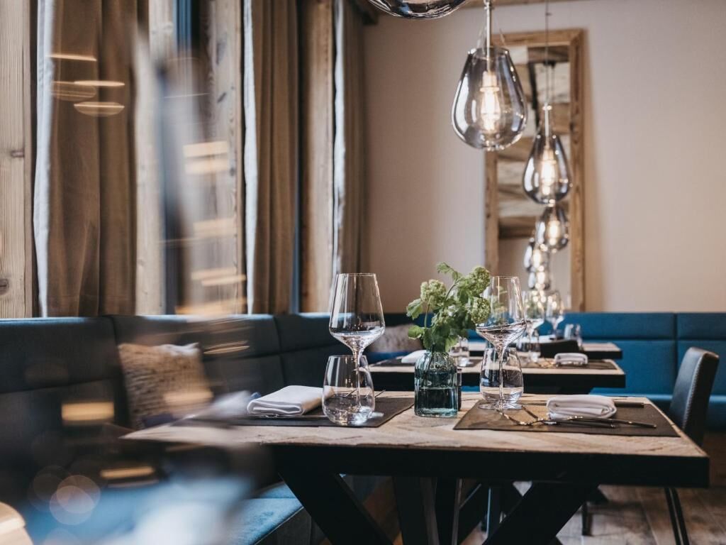 A restaurant with wooden tables, blue cushioned seating, and hanging pendant lights.