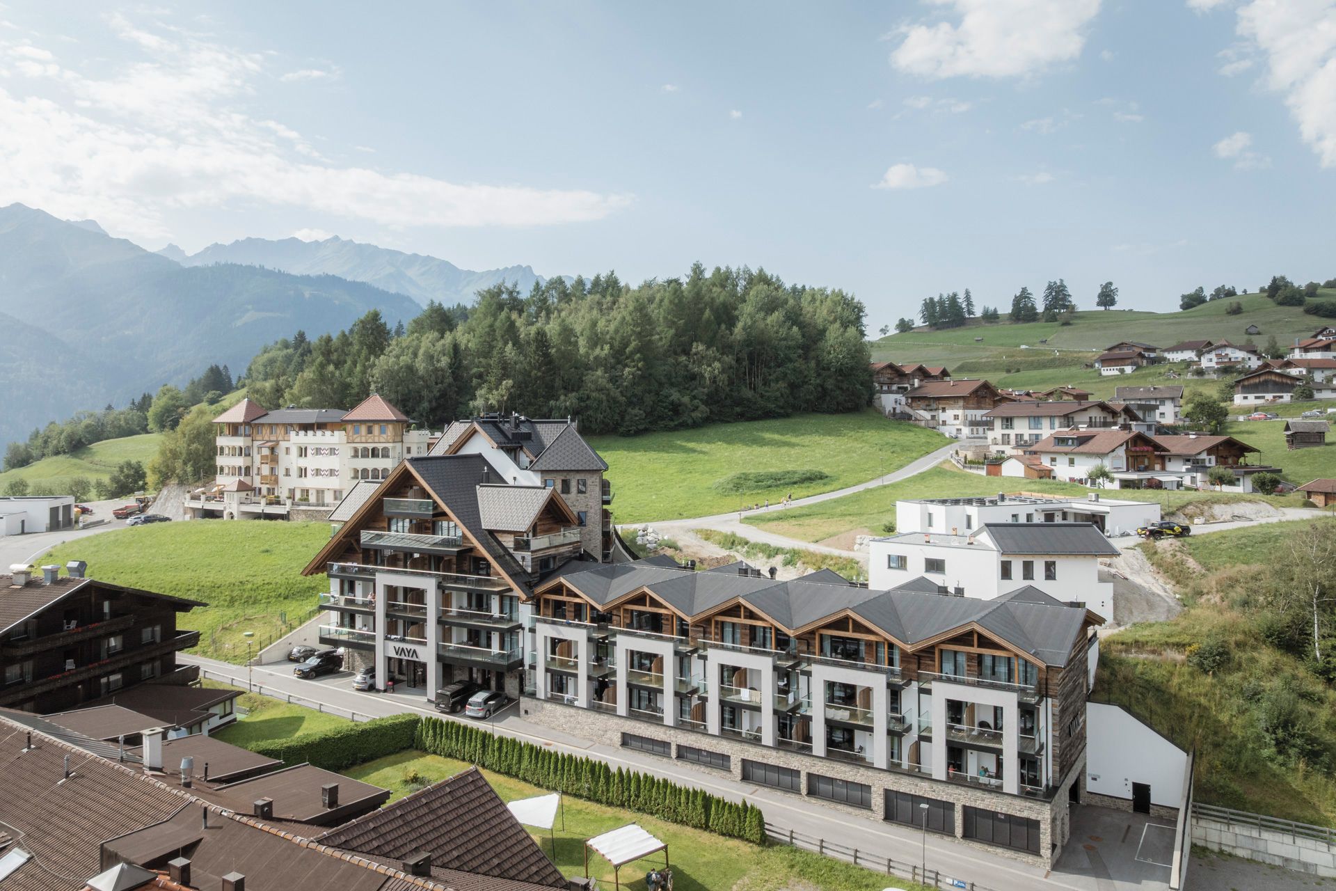 Un hôtel moderne à étages, doté de balcons et offrant une vue sur un paysage montagneux.