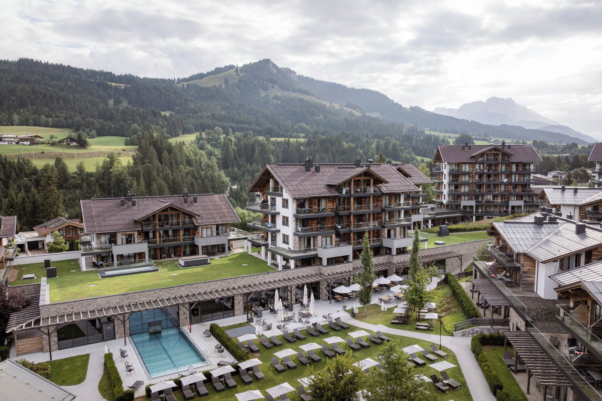 Un hotel con varias construcciones, piscina y zonas de estar al aire libre.