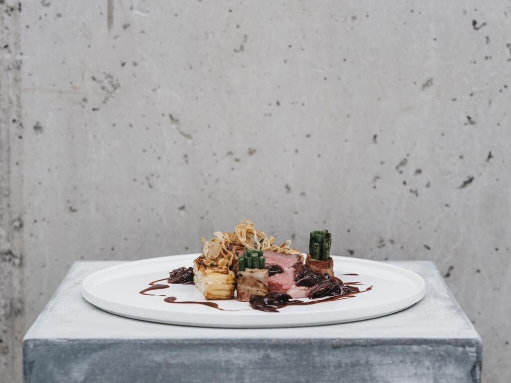 Un plato de comida sobre una fuente blanca, con un fondo gris.