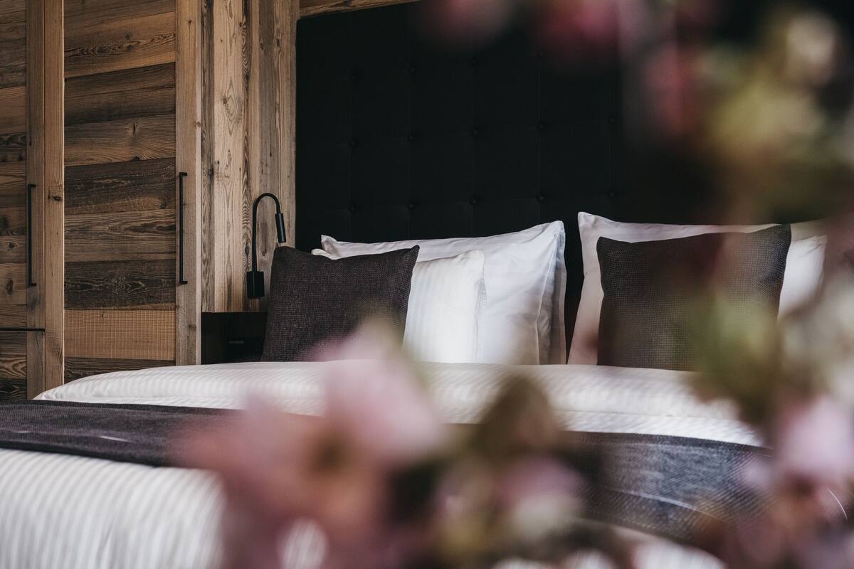 A bedroom with a bed, wooden wardrobe, and a black headboard.