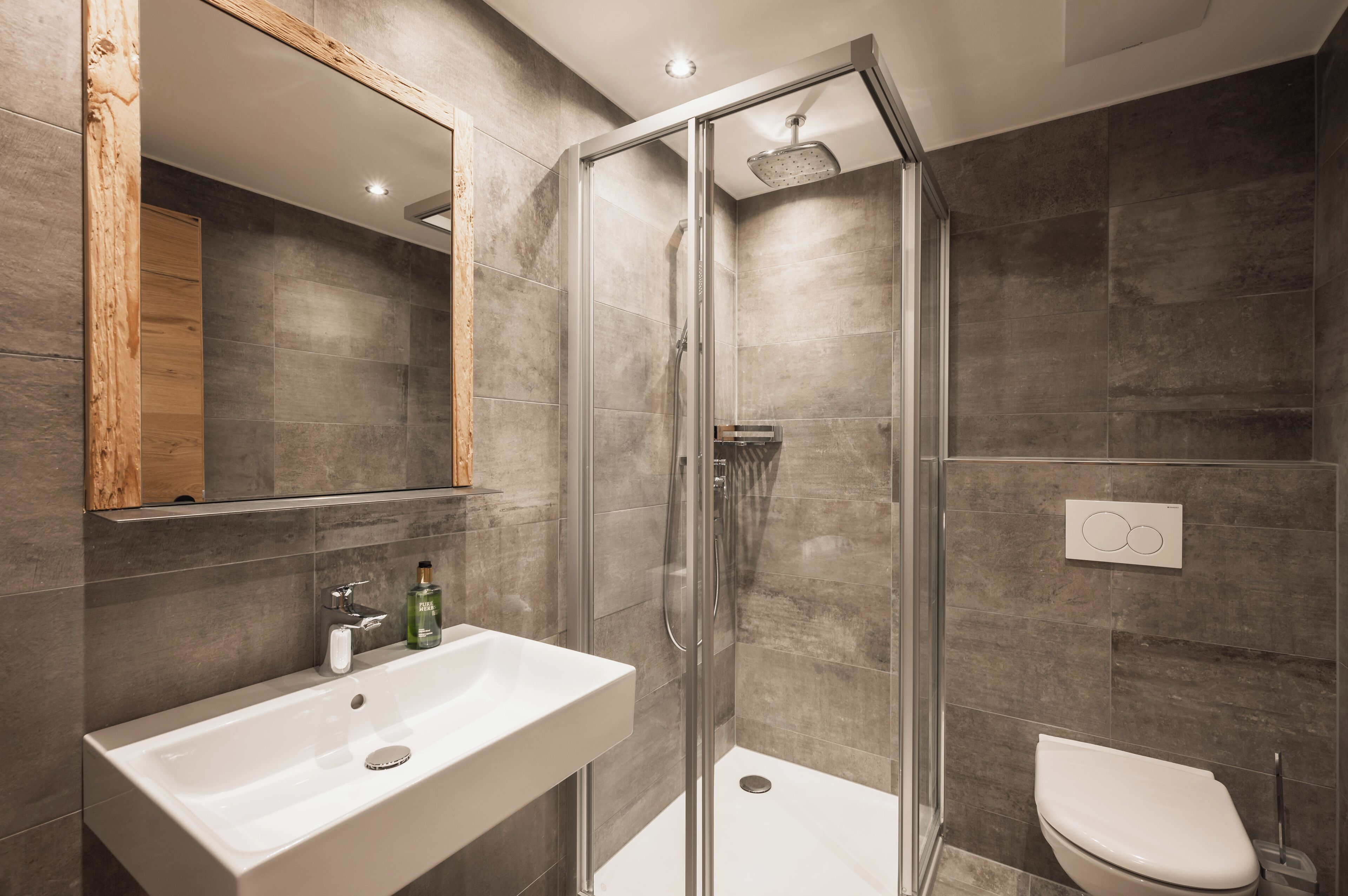 Un baño moderno con ducha envuelta en vidrio, un lavabo blanco y un inodoro.